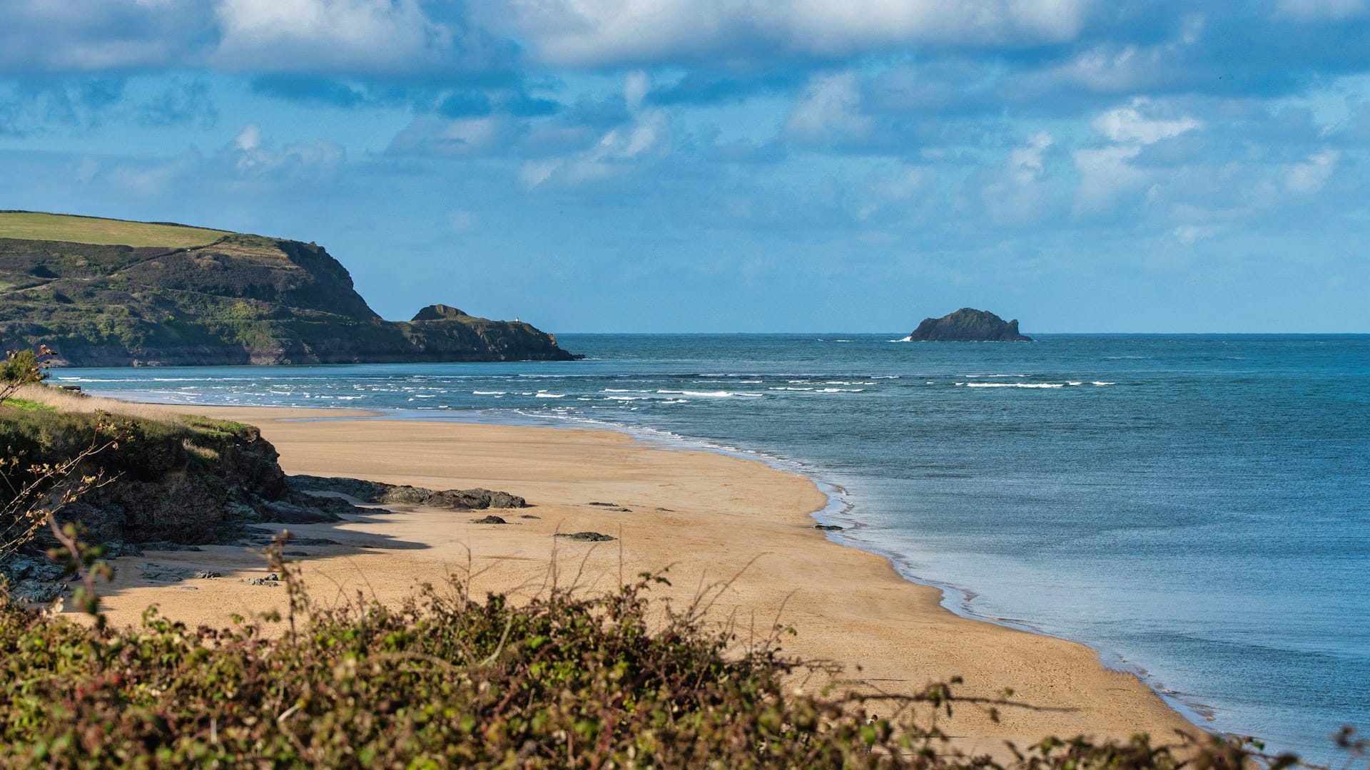 Cliff-top view of a sandy beach and blue sea on the Cornish coast near Padstow