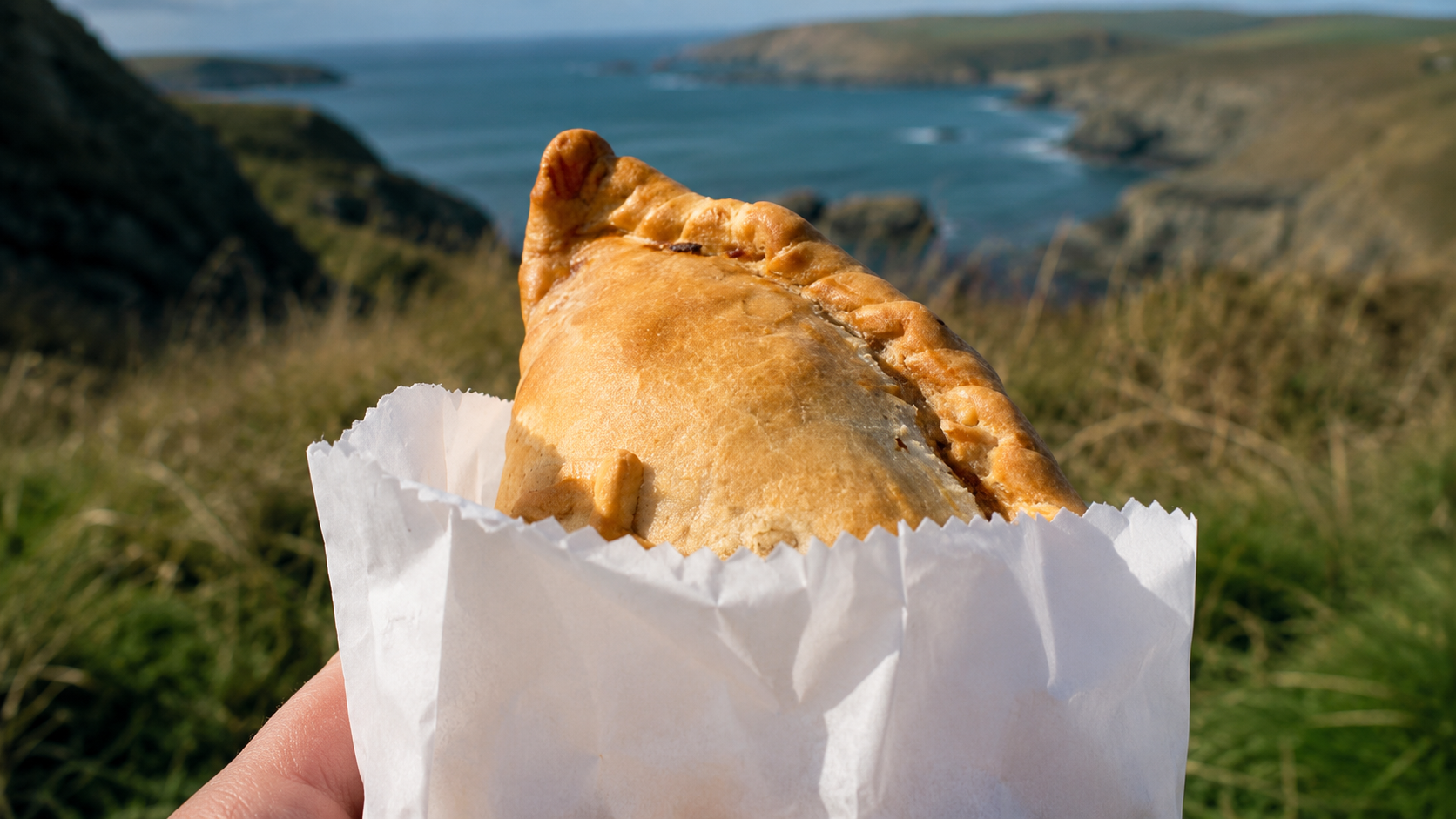 A traditional Cornish pasty with a crimped edge being held in Cornwall